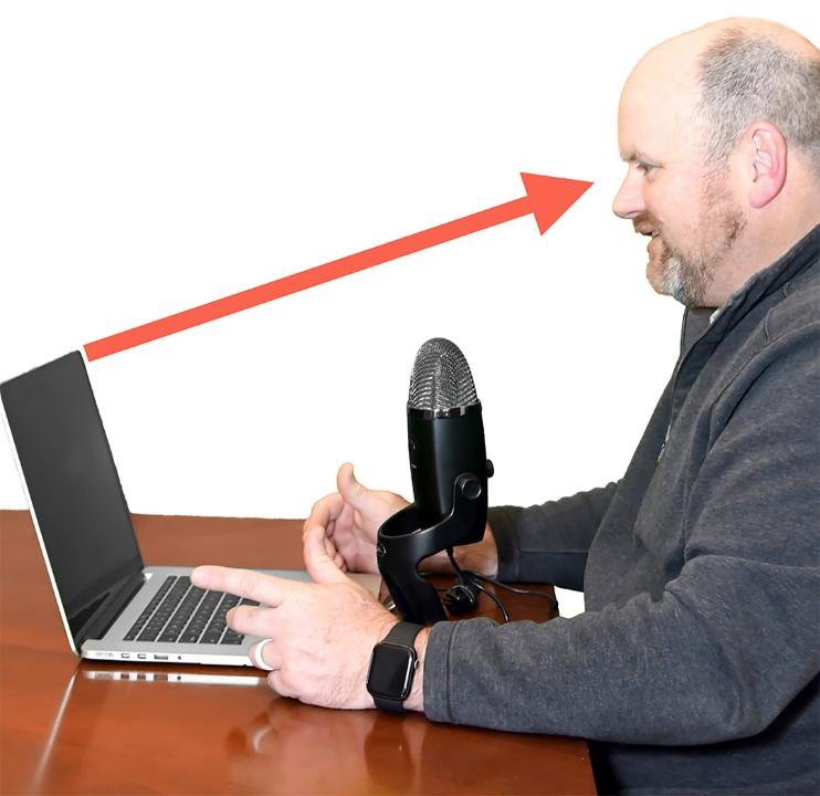 Fig. 3a: Lifting the computer higher will provide a much better camera angulation and framing of the presenter. An external microphone pictured here should be positioned as close as possible between 20 - 50 cm away from your voice